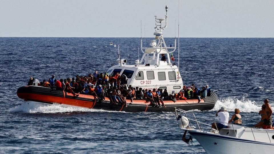 FILE PHOTO: An Italian Coast Guard vessel carrying migrants rescued at sea passes near a tourist boat, on the Sicilian island of Lampedusa, Italy, September 18, 2023. REUTERS/Yara Nardi/File Photo