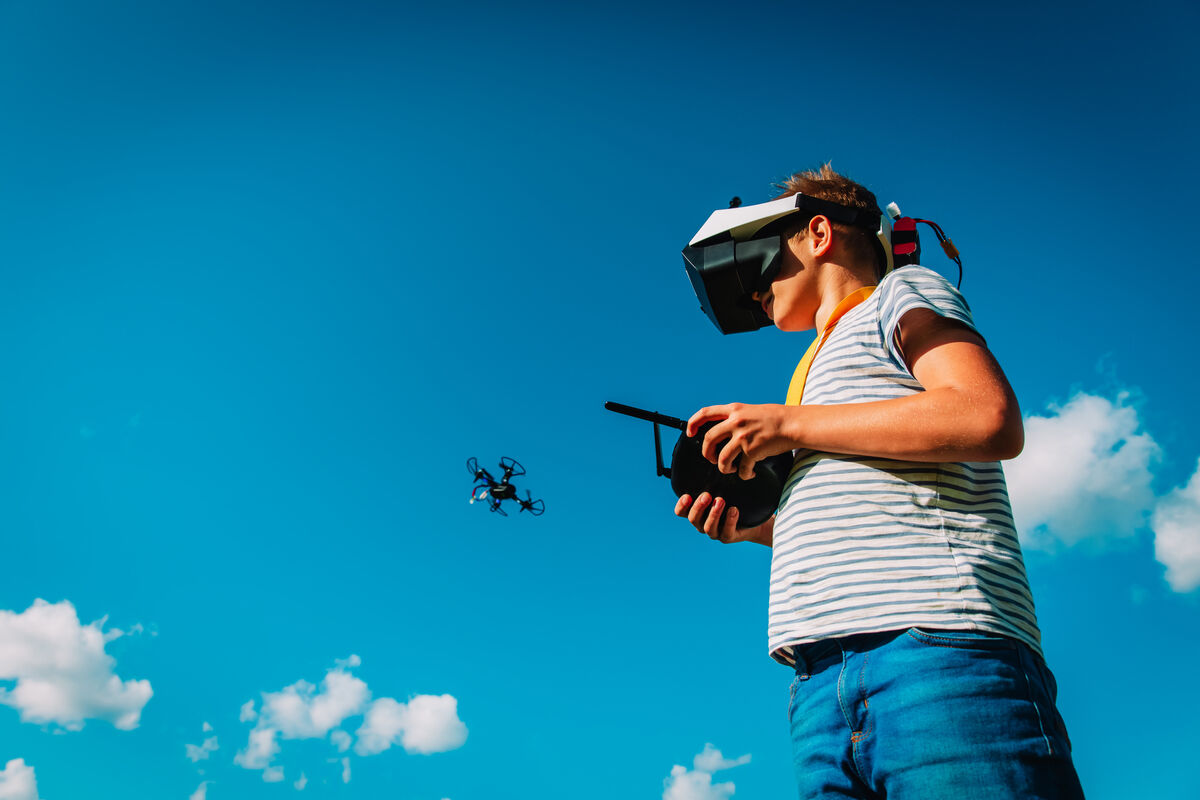 boy flying drone in virtual reality glasses in nature, kids learning technology