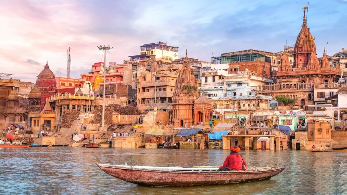 Ancient Varanasi city architecture at sunset with view of sadhu baba enjoying a boat ride on river Ganges.