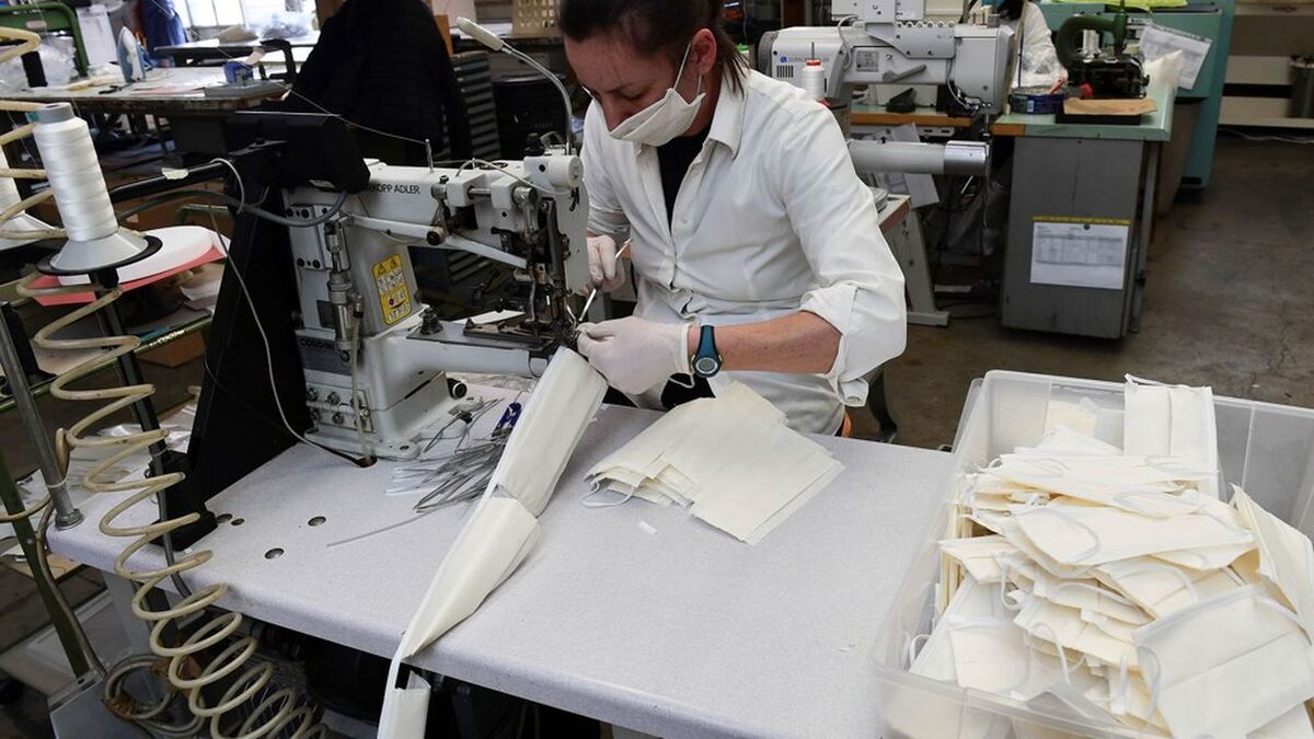 An employee wearing a face mask sews surgical masks at a leather workshop turned into a mask factory, close to Vigevano, Lombardy, on March 19, 2020 during the country's lockdown within the new coronavirus pandemic. - A crafts company specialized in the production of leather goods and accessories for the automotive and clothing sector, has now turned its activity to the production of surgical masks on behalf of a company from the nearby town of Galliate, in the wake of the needs following the coronavirus pandemic. (Photo by MIGUEL MEDINA / AFP)